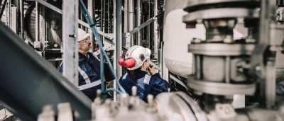 Werknemers in beschermende kleding inspecteren apparatuur in een industriële omgeving.