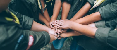 Verzameling handen van kinderen in groene uniformen die samenkomen.