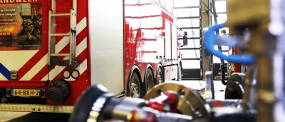 Brandweerwagen in garage, met focus op slangen en andere uitrusting op de voorgrond.