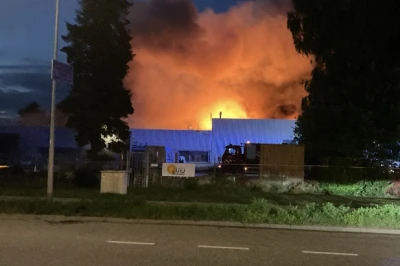 Groot vuur met oranje vlammen en rook boven een gebouw bij nacht.