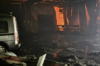 Verwoeste binnenruimte met rokerige lucht en een brandende achterdeur.