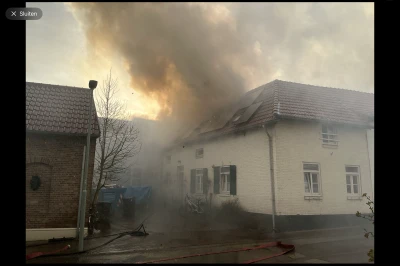 Zwartgrijze rook stijgt op boven een brand in een gebouw.