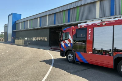 Een brandweerwagen staat geparkeerd voor een kleurrijk gebouw.