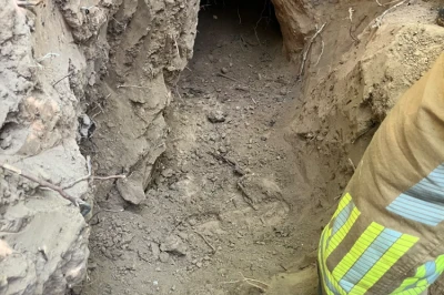 Tunnelsleuf in de grond met een persoon in een geel uniform aan de zijkant.