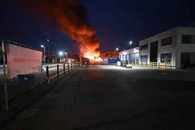 Grote vlammen in de lucht bij een industrieel terrein in de nacht.