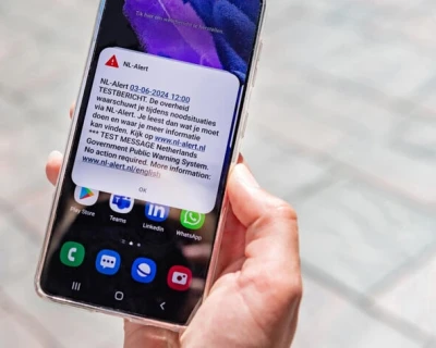 Een hand houdt een smartphone met een melding op een straat met stenen.
