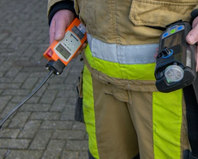 Een brandweerman houdt twee meetinstrumenten vast, met betrekking tot mogelijk gaslek